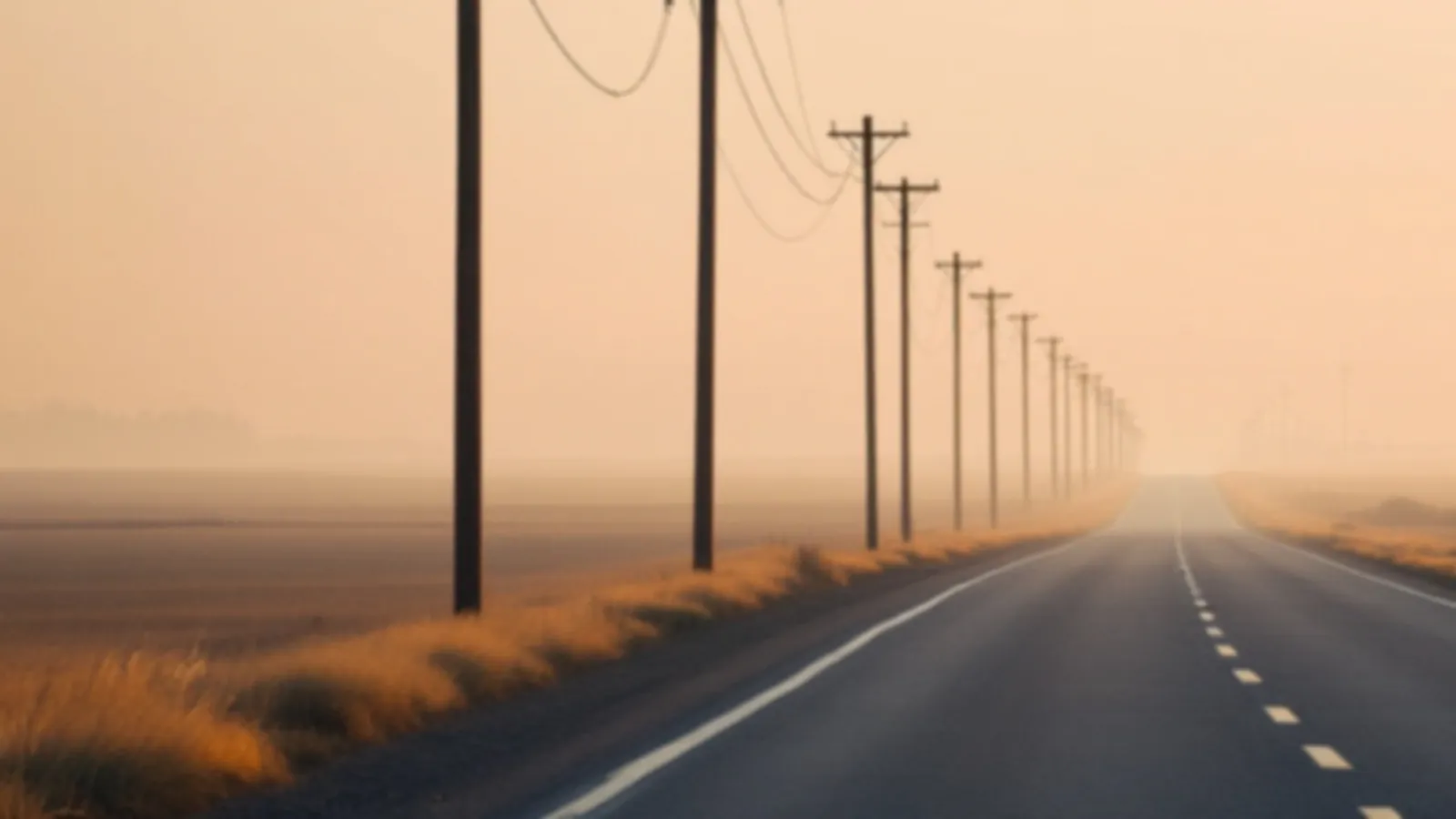 A long straight prairie road with wooden telephone poles under a big pale morning sky, the PistonQuotes view of loans until payday, $100 – $5,000